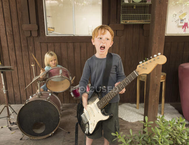 Діти грають на гітарі та барабанах у групі — стокове фото