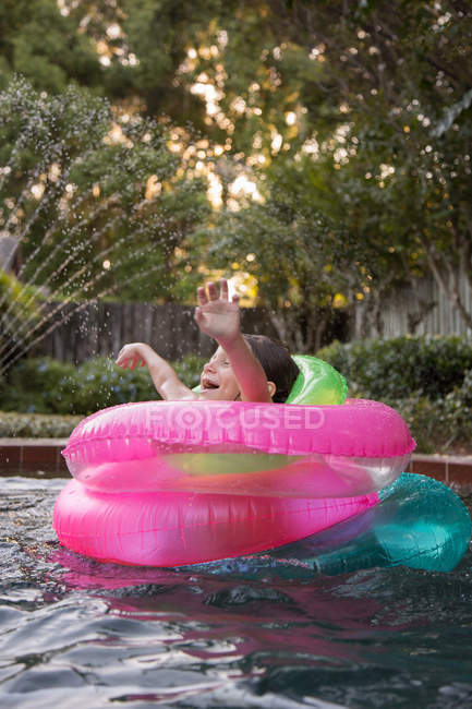 Jeune fille au milieu des anneaux gonflables dans la piscine extérieure — Photo de stock