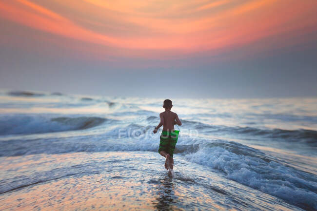 Junge läuft bei Sonnenuntergang ins Meer, North Myrtle Beach, South Carolina, Vereinigte Staaten — Stockfoto