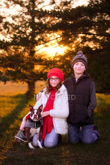 Portrait of girl and boy, with boston terrier dog, outdoors — Stock Photo