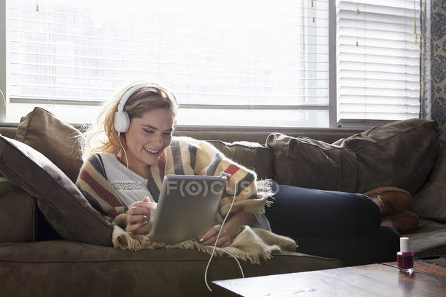 Donna che utilizza tablet digitale sul divano — Foto stock