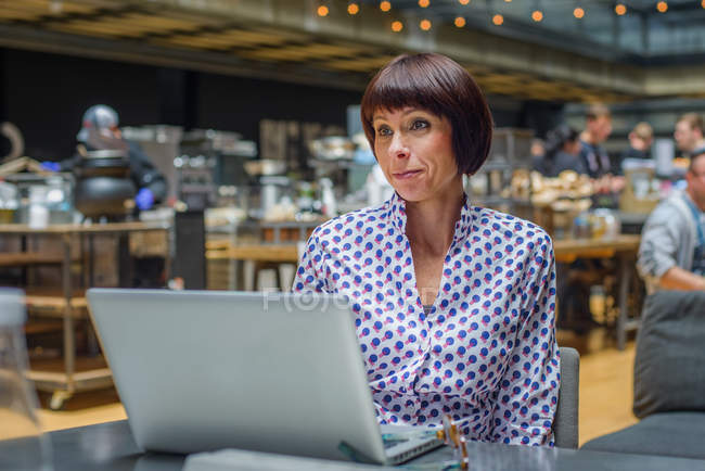 Portrait of mature woman using laptop in cafe — Stock Photo