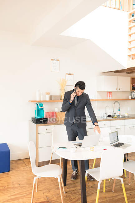 Giovane adulto uomo d'affari che fa smartphone chiamata in ufficio moderno — Foto stock