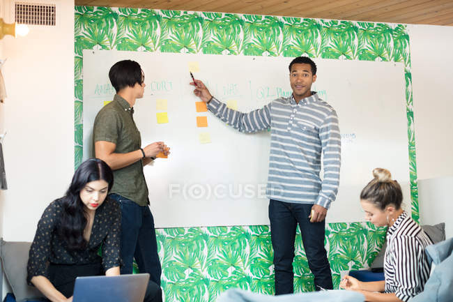 Colleagues working with whiteboard in creative office — Stock Photo
