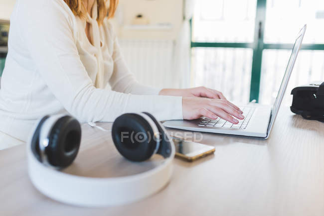 Середина молодої жінки за столом друкує на ноутбуці — стокове фото