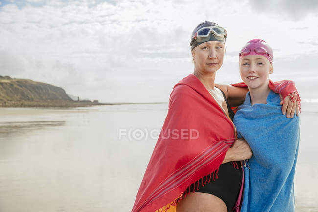 Madre e figlia avvolte in scialli sulla spiaggia — Foto stock