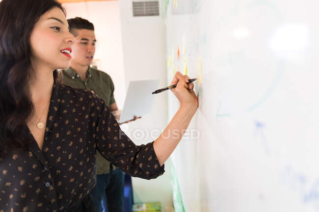 Young businesswoman writing on whiteboard adhesive notes — Stock Photo