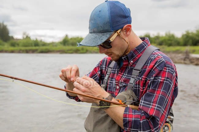 Hombre preparando cebo para la pesca con mosca, Clark Fork, Montana - foto de stock