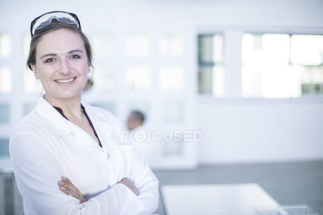 Portrait of female laboratory worker, arms folded, smiling — Stock Photo