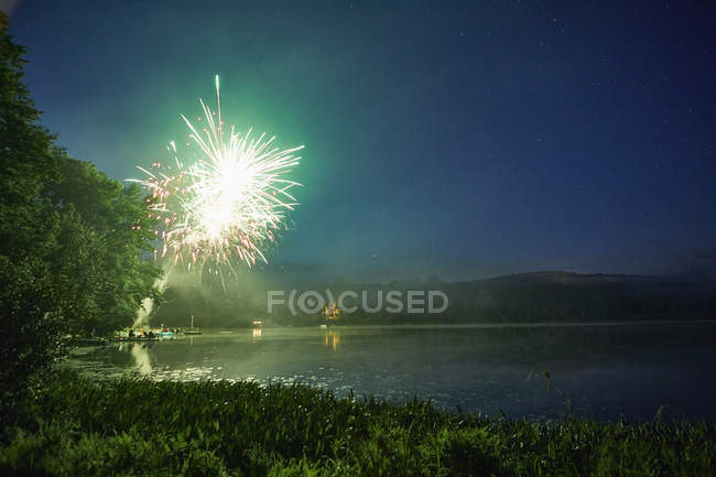 Feux d'artifice explosant au-dessus du lac au crépuscule — Photo de stock