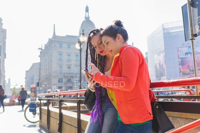 Mujeres en vacaciones de la ciudad con smartphone, Milán, Italia - foto de stock
