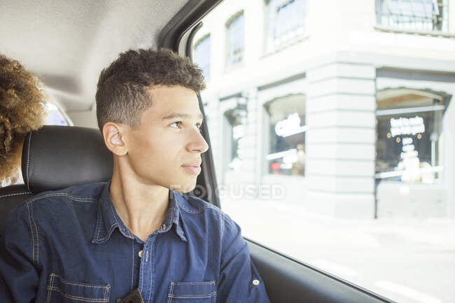 Jeune homme assis sur le siège passager de la voiture, regardant par la fenêtre — Photo de stock