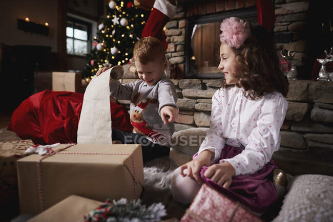 Мальчик и девочка сортируют рождественские подарки, список мальчиков — стоковое фото