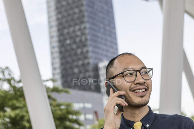 Businessman smiling and talking on smartphone outdoors — Stock Photo