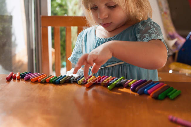 Girl lining up crayons in row — Stock Photo