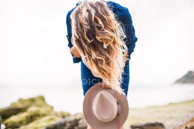 Mulher em flexão costeira sobre a fixação segurando chapéu — Fotografia de Stock