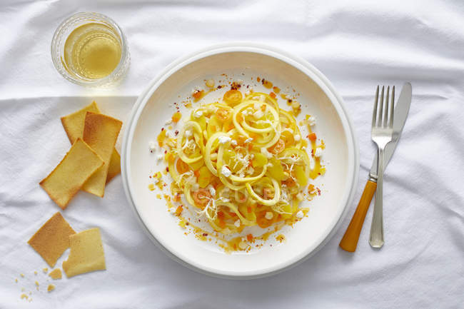 Massa de abóbora amarela espiralizada com tomate cereja amarelo, feta, pimenta laranja e uma coulis de pimenta laranja — Fotografia de Stock