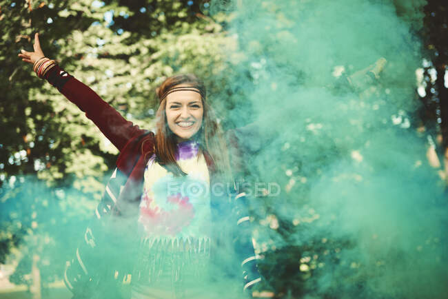 Young boho woman dancing with green smoke flare  at festival — Stock Photo