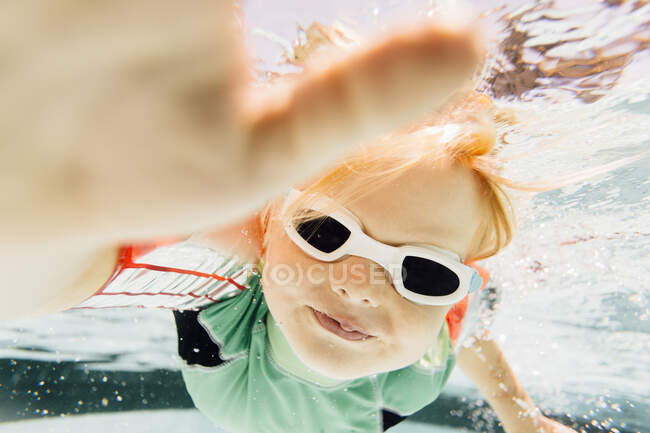 Ragazzo che nuota sott'acqua in piscina, vista subacquea — Foto stock