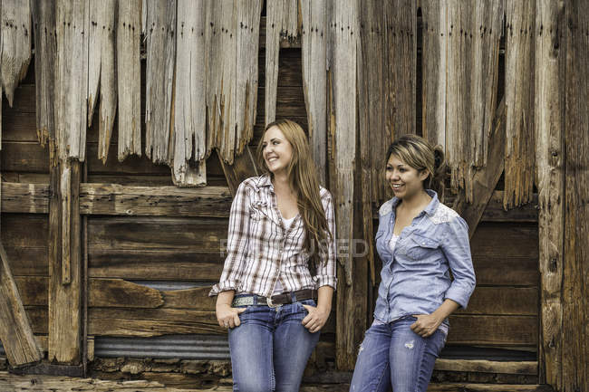 Two young women standing outside barn, smiling — Stock Photo