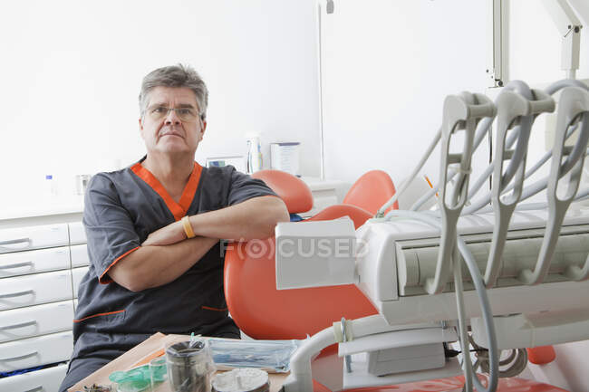 Dentista sentado junto a la silla dental - foto de stock