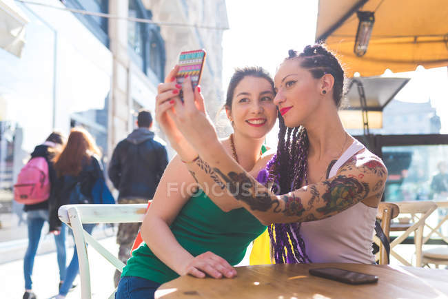 Женщины на отдыхе в кафе на открытом воздухе с селфи, Милан, Италия — стоковое фото