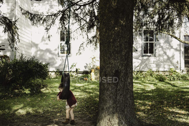 Menina no balanço do pneu pendurado na árvore — Fotografia de Stock