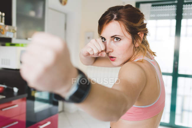 Young woman doing boxing training in kitchen — Stock Photo