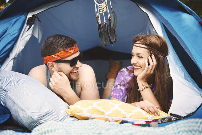 Молодая пара бохо лежит в палатке на фестивале — стоковое фото