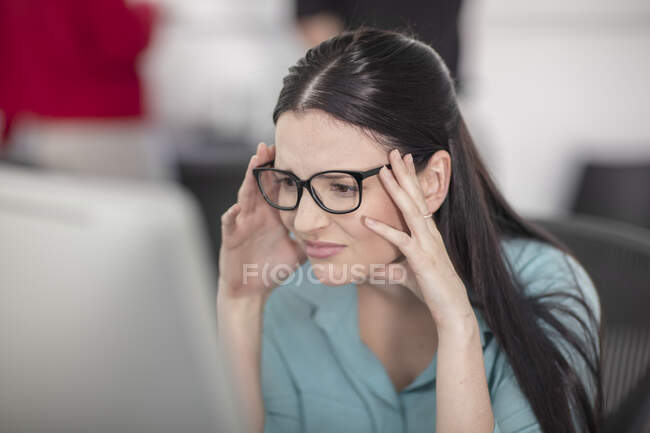 Stressé jeune employée de bureau regardant l'ordinateur de bureau — Photo de stock