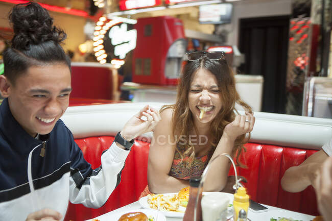 Three young friends sitting in diner, laughing — Stock Photo