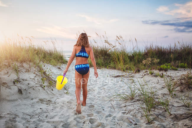 Ragazza con secchio camminare sulla spiaggia — Foto stock