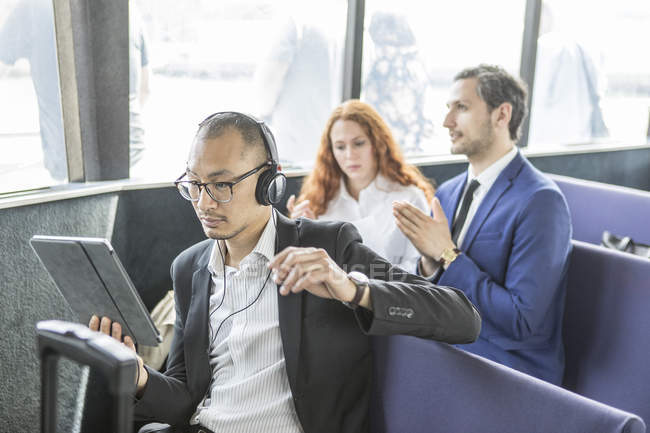 Empresário em fones de ouvido olhando para tablet digital em balsa de passageiros — Fotografia de Stock