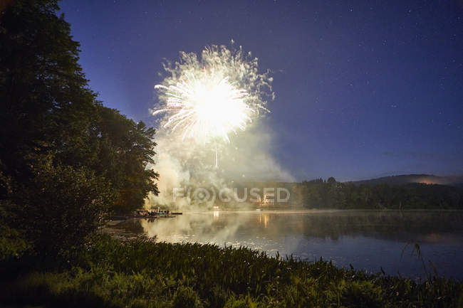 Феєрверк вибухають озеро в сутінках — стокове фото