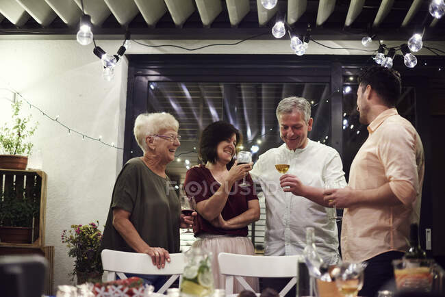Grupo de pessoas em pé ao lado da mesa de jantar, segurando copos de vinho — Fotografia de Stock