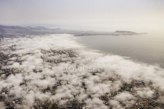 Vue aérienne de la ville et de la côte à travers le paysage nuageux, Lima, Pérou — Photo de stock