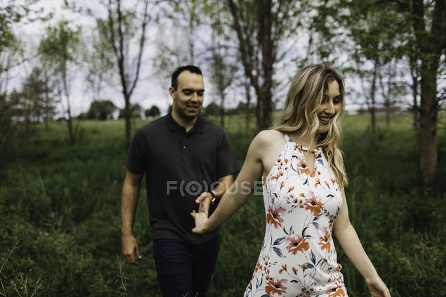Romantic couple holding hands in field — Stock Photo