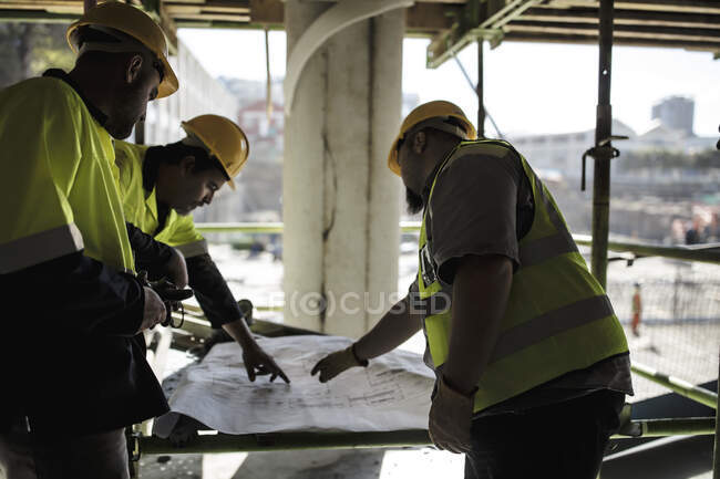 Bauarbeiter schauen sich Pläne an — Stockfoto