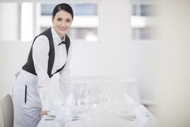 Retrato de camarera cerca de mesa servida en restaurante - foto de stock
