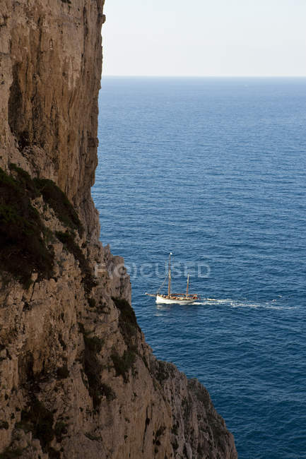Vista panorámica de los acantilados costeros y el barco, Capo Caccia, Cerdeña, Italia - foto de stock