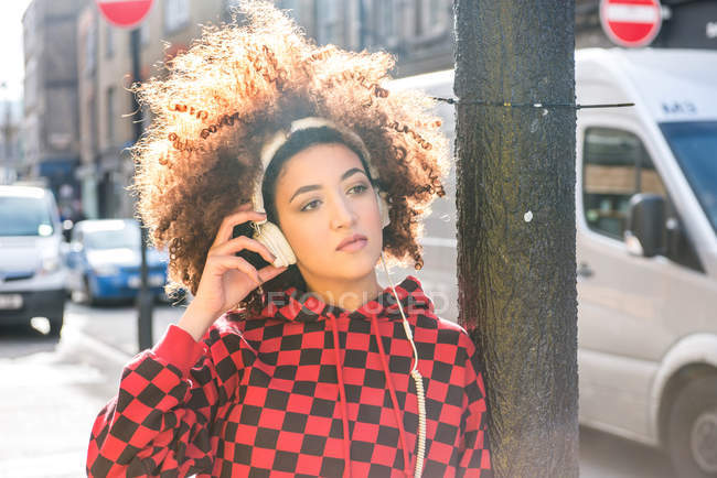Retrato de mujer joven con auriculares al aire libre - foto de stock