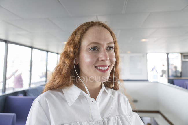 Усміхнена бізнес-леді в навушниках на пасажирському поромі — стокове фото