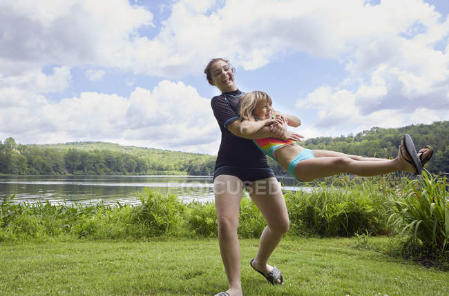 Girls playing on grass beside lake — Stock Photo