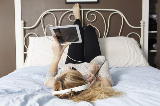 Femme utilisant une tablette numérique sur le lit — Photo de stock