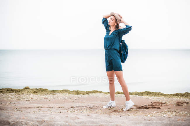 Mulher de chapéu em pé perto da costa — Fotografia de Stock