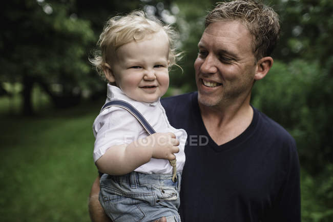 Porträt eines Mannes, der seinen kleinen Sohn trägt — Stockfoto