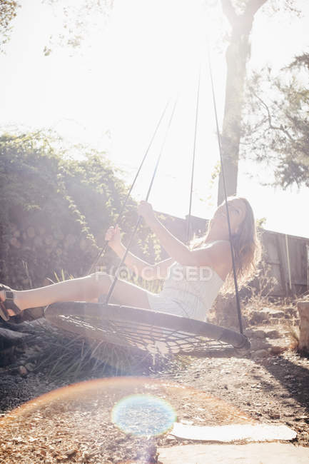 Jeune femme balançant sur jardin balançoire — Photo de stock