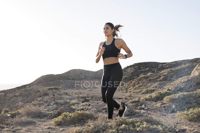 Jeune coureuse sur piste de terre dans un paysage aride, Las Palmas, Îles Canaries, Espagne — Photo de stock