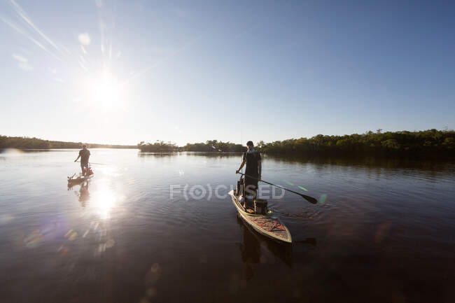 Two men paddle boarding on water — Stock Photo