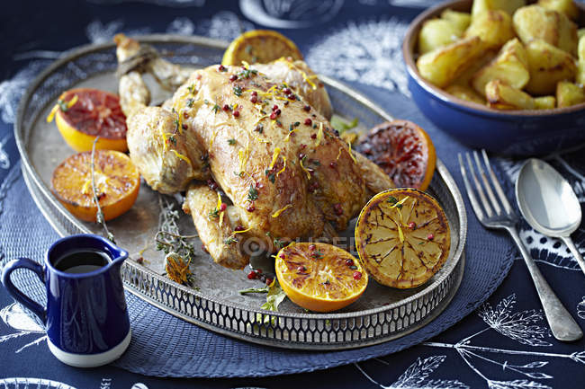 Roast chicken with glazed citrus fruits on serving tray — Stock Photo